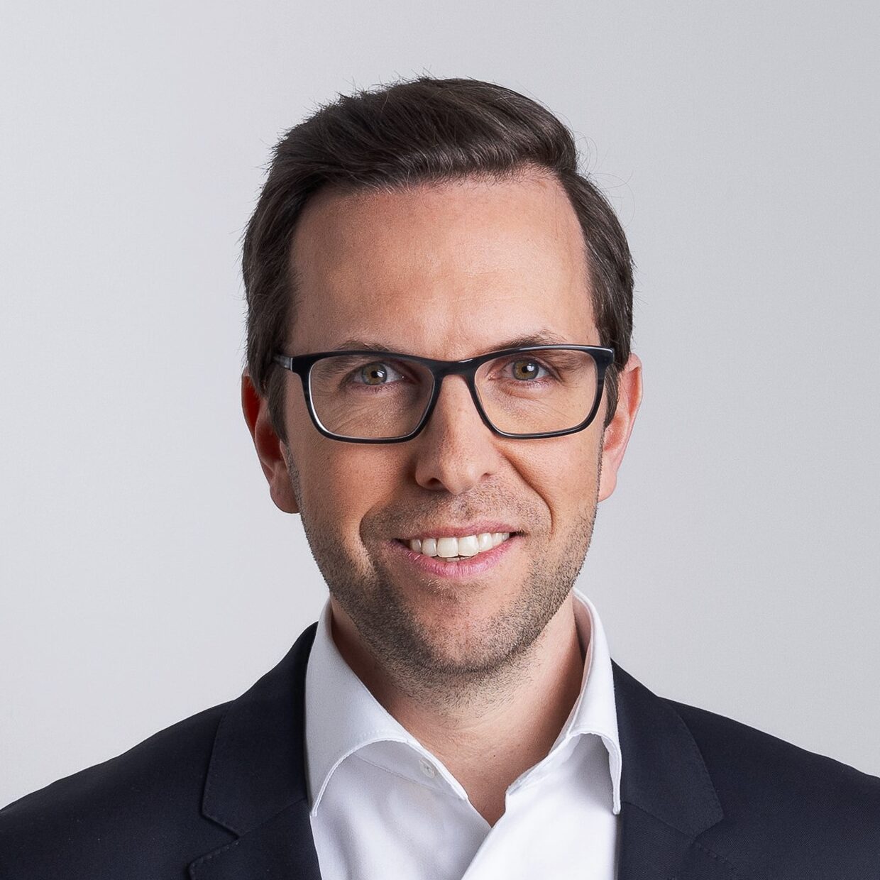 Portraitfoto eines Mannes mit dunkler Brille, dunklem Sakko