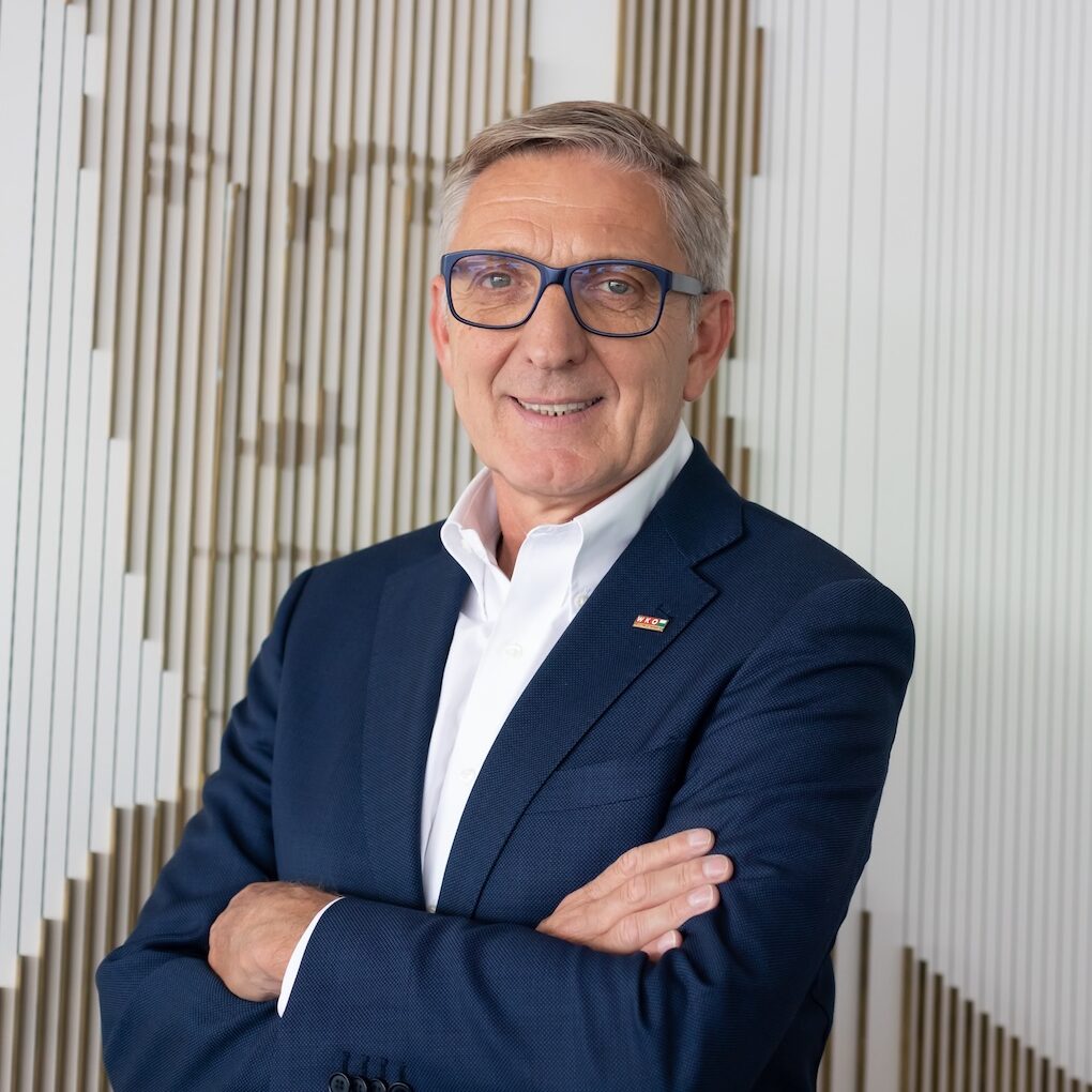 Portraitfoto eines Mannes mit blauer Brille im blauen Anzug mit weißem Hemd