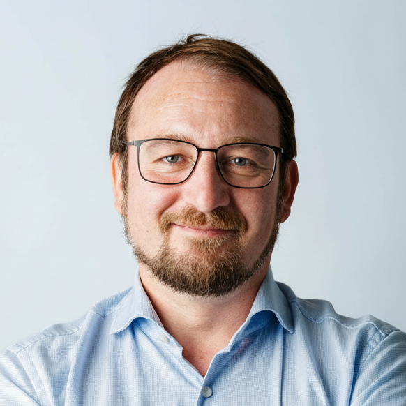Portraitfoto eines Mannes mit dunkler Brille und hellblauem Hemd