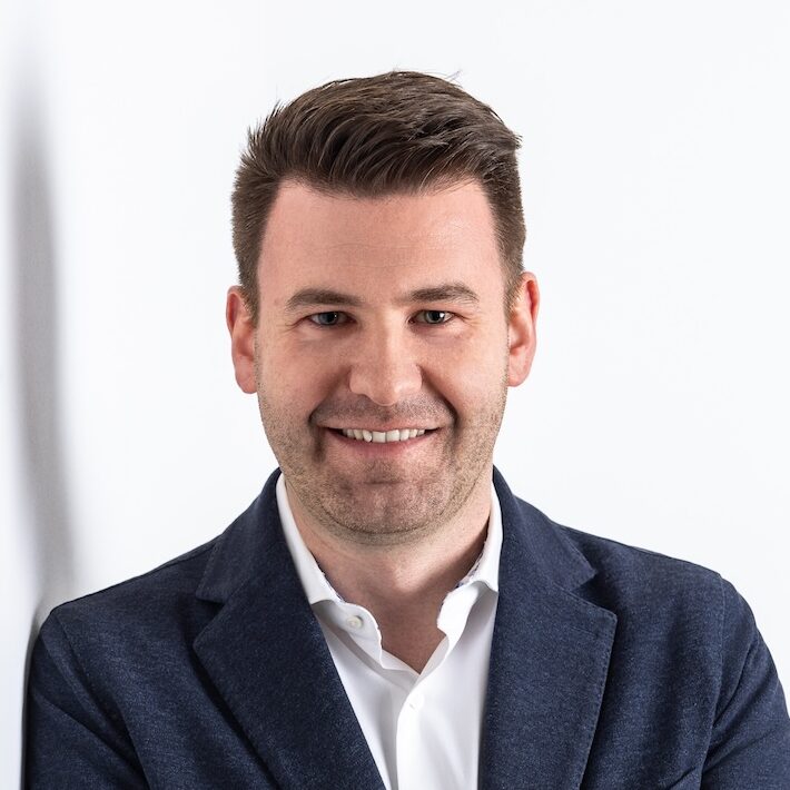 Portraitfoto eines Mannes mit dunklem Sakko und weißem Hemd